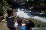 Sejumlah anak mengamati Sungai Anak Cikapundung yang tercemar limbah di Batununggal, Bandung Jawa Barat, Rabu (25/9/2019). Kondisi air aliran Sungai Anak Cikapundung yang bermuara ke Sungai Citarum tersebut berbusa dan mengeluarkan bau yang diduga akibat limbah industri sehingga menganggu aktivitas warga di sekitar sungai. ANTARA JABAR/Raisan Al Farisi/agr