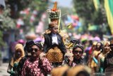 Warga menandu seorang anak berikut gunungan berisi hasil bumi dan jajanan pasar saat tradisi Kebur Banyu Ubalan di kawasan wisata sumber air Ubalan, Desa Jarak, Kediri, Jawa Timur, Minggu (29/9/2019). Tradisi berebut gunungan dan saling siram air pada bulan Suro penanggalan Jawa tersebut sebagai upaya warga sekitar menjaga kelestarian mata air sekaligus sarana promosi wisata. Antara Jatim/Prasetia Fauzani/zk