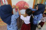 Pelajar dibantu guru menempelkan kertas bermotif batik di dinding SD Negeri Pesantren 2, Kota Kediri, Jawa Timur, Selasa (1/10/2019). Kegiatan menghias sekolah dengan nuansa batik tersebut bertujuan memperkenalkan seni budaya batik kepada pelajar sekaligus memperingati Hari Batik Nasional. Antara Jatim/Prasetia Fauzani/zk.