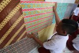 Pelajar menempelkan kertas bermotif batik di dinding SD Negeri Pesantren 2, Kota Kediri, Jawa Timur, Selasa (1/10/2019). Kegiatan menghias sekolah dengan nuansa batik tersebut bertujuan memperkenalkan seni budaya batik kepada pelajar sekaligus memperingati Hari Batik Nasional. Antara Jatim/Prasetia Fauzani/zk.