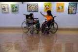 Dua penyandang disabilitas melihat pameran lukisan hasil karya mereka dan rekannya dalam Festival Kesenian Bali (FKB) Penyandang Disabilitas di Taman Budaya Bali (Art Centre), Denpasar, Bali, Jumat (4/10/2019). Kegiatan yang berlangsung pada 4-6 Oktober 2019 tersebut untuk memberikan ruang dan semangat kepada para penyandang disabilitas dalam menampilkan kreativitas mereka di bidang seni lukis, pameran kerajinan UMKM dan pentas kesenian. ANTARA FOTO/Nyoman Hendra Wibowo/nym.