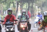 Pengendara sepeda motor menggunakan masker pelindung pernapasan saat melintas di jalan Brig Jend Hasan Basri yang di selimuti kabut asap di Banjarmasin, Kalimantan Selatan, Senin (14/10/2019).Kota Banjarmasin dan sekitarnya kembali di selimuti kabut asap akibat kebakaran hutan dan lahan (karhutla) di sejumlah wilayah Kalsel.Foto Antaranews Kalsel/Bayu Pratama S.