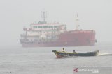 Perahu mesin melintas di Sungai Barito yang di selimuti kabut asap di Banjarmasin, Kalimantan Selatan, Senin (14/10/2019).Kota Banjarmasin dan sekitarnya kembali di selimuti kabut asap akibat kebakaran hutan dan lahan (karhutla) di sejumlah wilayah Kalsel.Foto Antaranews Kalsel/Bayu Pratama S.