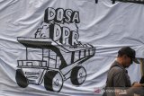 Warga melintas di depan spanduk Dosa DPR saat unjuk rasa damai di depan Gedung Sate, Bandung, Jawa Barat, Kamis (17/10/2019). Aksi tersebut untuk menyampaikan aspirasi terhadap sejumlah permasalahan di Indonesia dan menuntut dicabutnya sejumlah RUU bermasalah seperti RKUHP. RUU  Minerba, serta segera diterbitkannya Perppu KPK. ANTARA JABAR/Novrian Arbi/agr