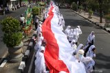 Santri membawa bendera merah putih sepanjang 1000 meter saat pawai peringatan Hari Santri Nasional di Sidoarjo, Jawa Timur, Minggu (20/10/2019). Kegiatan yang diikuti oleh ribuan santri dan guru dari berbagai sekolah dan pesantren tersebut untuk memperingati Hari Santri Nasional. Antara Jatim/Umarul Faruq/zk