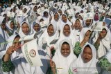 Sejumlah siswi madrasah mengibarkan bendera saat mengikuti upacara Peringatan Hari Santri Nasional Tingkat Provinsi Jawa Barat 2019 di Lapangan Gasibu, Bandung, Jawa Barat, Senin (22/10/2019). Pemerintah Jawa Barat memberikan sejumlah bantuan motor listrik dan hadiah umroh bagi santri, pondok pesantren serta DKM se-Jawa Barat pada Peringatan Hari Santri Nasional 2019 yang bertema Santri Indonesia Untuk Perdamaian Dunia. ANTARA FOTO/Novrian Arbi/agr