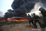 Satgas Karhutla dari TNI, Polri bersama relawan pemadam kebakaran berupaya memadamkan kebakaran lahan yang menjalar ke tumpukkan ban bekas di Kecamatan Gambut, Kabupaten Banjar, Kalimantan Selatan, Selasa (22/10/2019). Kencangnya angin serta sulitnya sumber air di lokasi lahan terbakar membuat api cepat meluas hingga menjalar ke tumpukkan ban bekas yang mengakibatkan asap hitam pekat membumbung tinggi dan menyulitkan petugas untuk memadamkan kebakaran tersebut. Foto Antaranews Kalsel/Bayu Pratama S.