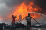 Satgas Karhutla dari TNI, Polri bersama relawan pemadam kebakaran berupaya memadamkan kebakaran lahan yang menjalar ke tumpukkan ban bekas di Kecamatan Gambut, Kabupaten Banjar, Kalimantan Selatan, Selasa (22/10/2019). Kencangnya angin serta sulitnya sumber air di lokasi lahan terbakar membuat api cepat meluas hingga menjalar ke tumpukkan ban bekas yang mengakibatkan asap hitam pekat membumbung tinggi dan menyulitkan petugas untuk memadamkan kebakaran tersebut. Foto Antaranews Kalsel/Bayu Pratama S.