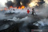 Satgas Karhutla dari TNI, Polri bersama relawan pemadam kebakaran berupaya memadamkan kebakaran lahan yang menjalar ke tumpukkan ban bekas di Kecamatan Gambut, Kabupaten Banjar, Kalimantan Selatan, Selasa (22/10/2019). Kencangnya angin serta sulitnya sumber air di lokasi lahan terbakar membuat api cepat meluas hingga menjalar ke tumpukkan ban bekas yang mengakibatkan asap hitam pekat membumbung tinggi dan menyulitkan petugas untuk memadamkan kebakaran tersebut. Foto Antaranews Kalsel/Bayu Pratama S.