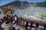 Pengunjung berfoto dengan latar belakang kawah Gunung Tangkuban Parahu di Kabupaten Subang, Jawa Barat, Selasa (22/10/2019). Setelah ditutup selama kurang lebih tiga bulan, Taman Wisata Alam Gunung Tangkuban Parahu kembali dibuka karena status Gunung Tangkuban Parahu dinyatakan normal dan aman untuk dikunjungi oleh wisatawan. ANTARA FOTO/Raisan Al Farisi/agr