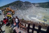 Pengunjung berfoto dengan latar belakang kawah Gunung Tangkuban Parahu di Kabupaten Subang, Jawa Barat, Selasa (22/10/2019). Setelah ditutup selama kurang lebih tiga bulan, Taman Wisata Alam Gunung Tangkuban Parahu kembali dibuka karena status Gunung Tangkuban Parahu dinyatakan normal dan aman untuk dikunjungi oleh wisatawan. ANTARA FOTO/Raisan Al Farisi/nym.