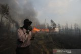 Pihak kepolisian bersiaga saat terjadi kebakaran lahan yang menjalar kerumah warga di kawasan Pematang, Kecamatan Gambut, Kabupaten Banjar, Kalimantan Selatan, Rabu (23/10/2019). Kebakaran hutan dan lahan (Karhutla) di kawasan tersebut menghanguskan satu buah rumah yang dihuni satu kepala keluarga dengan empat jiwa. Foto Antaranews Kalsel/Bayu Pratama S.