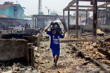 Seorang anak kecil membawa  barang-barang yang bisa digunakan pasca kebakaran di Pasar Jatisari, Karawang, Jawa Barat, Jumat (25/10/2019). Pemerintah Kabupaten Karawang berencana merelokasi para pedagang sebagai solusi jangka pendek dan akan membagunan ulang pasar tersebut guna mengembalikan perekonomian masyarakat. ANTARA JABAR/M Ibnu Chazar/agr