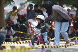 Seorang anak dibimbing orang tuanya mengikuti kompetisi Push Bike di Kota Kediri, Jawa Timur, Sabtu (26/10/2019). Kompetisi balap sepeda tanpa pedal tersebut diikuti sejumlah anak usia 2-5 tahun dari sejumlah daerah. Antara Jatim/Prasetia Fauzani/zk.