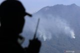 Satgas Karhutla Ijen dari TNI AD memantau Helikopter Badan Nasional Penanggulangan Bencana (BNPB) melakukan water bombing di atas hutan  yang terbakar di Cagar Alam Merapi Ungup-ungup Banyuwangi, Jawa Timur, Minggu (27/10/2019). Satgas Karhutla Ijen terus melakukan upaya pemadaman dari darat maupun udara agar kebakaran lahan dan hutan tidak semakin meluas. Antara Jatim/Budi Candra Setya/zk.