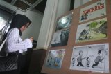 Pengunjung melihat lukisan karikatur yang dipajang dalam pameran bertajuk Saweran Kartun dengan tema Demokrasi Dikorupsi di Balaikota Malang, Jawa Timur, Kamis (31/10/2019). Pameran yang  merupakan upaya sosialisasi bahaya korupsi sekaligus bentuk kritik terhadap perilaku korupsi di masyarakat tersebut diadakan selama tiga hari dengan menampilkan 80 karya karikatur, komik strip dan kartun dari 30 kartunis dari berbagai daerah. Antara Jatim/Ari Bowo Sucipto/zk.