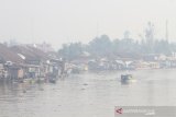 Kelotok (perahu bermesin) melintas di Sungai Martapura yang di selimuti kabut asap di Kota Banjarmasin, Kalimantan Selatan, Jumat (8/11/2019). Kebakaran hutan dan lahan (Karhutla) yang kembali terjadi di sejumlah daerah di Provinsi Kalsel menimbulkan kabut asap hingga menyelimuti Kota Banjarmasin. Foto Antaranews Kalsel /Bayu Pratama S.