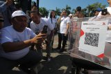 Warga memindai stiker 'QR Code' yang tertempel di kotak amal saat pemecahan rekor Museum Rekor-Dunia Indonesia (MURI) di Surabaya, Jawa timur, Sabtu (9/11/2019). Kegiatan penempelan 'QR Code' yang digelar Bank Indonesia yang bertujuan mempermudah warga untuk menyumbang rumah ibadah secara non tunai itu memecahkan rekor MURI 'Penempelan QR Code Terbanyak di Kotak Amal'. Antara Jatim/Didik S/ZK