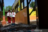 Siswa berada di depan ruang kelas 1 yang ambruk beberapa hari lalu di Sekolah Dasar Negeri Dukuh Klopo, Kecamatan Peterongan, Kabupaten Jombang, Jawa Timur, Selasa (12/11/2019). Pasca salah satu ruang kelas SDN Dukuh Klopo, ambruk lantaran usia bangunan yang cukup tua serta sudah lapuk. Siswa kelas 5 dan 2 harus belajar secara lesehan di ruang perpustakaan serta musala karena pihak sekolah khawatir, ruang kelas 2 dan 5 ikut terdampak sebab ruangannya berada di sebelah bangunan yang ambruk. Antara Jatim/Syaiful Arif/zk