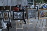 Pengunjung melihat-lihat karya seni perupa daerah dalam ajang pameran lukisan out door atau luar ruang bertajuk 