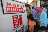 Warga dan pelajar PAUD memilih buku-buku dari Mobil Pintar (MoPi) Askrindo usai penyerahan bantuan MoPi untuk Paud Institute Jawa Timur dari PT Asuransi Kredit Indonesia (Askrindo) (Persero), di Surabaya, Jawa Timur, Senin (18/11/2019). Mobil Pintar Askrindo merupakan perpustakaan berjalan dilengkapi dengan sarana multi media, buku-buku bacaan serta alat peraga pendidikan yang digunakan untuk membangun budaya literasi sejak usia dini, dan memberikan akses membaca buku berkualitas untuk anak-anak di pelosok negeri. Antara Jatim/Didik S/ZK