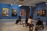 Pengunjung mengamati lukisan saat pameran tunggal pelukis Asri Noegroho di Indigo Art Space Madiun, Jawa Timur, Minggu (17/11/2019) malam. Pameran lukisan karya pelukis asal Surabaya bertema Tokoh tersebut akan berlangsung hingga 8 Desember 2019. Antara Jatim/Siswowidodo/zk