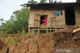 Merahwan (49) pemilik rumah berada di dalam rumahnya yang hampir amblas akibat erosi sungai di Desa Meutulang, Kecamatan Pantoe Reu, Aceh Barat, Aceh, Selasa (19/11/2019). Dampak banjir yang terjadi di Kabupaten setempat mengakibatkan amblasnya tebing sungai sepanjang 150 meter pada Sabtu (16/11), apabila pihak terkait tidak segera menangani peristiwa tersebut dapat mengancam rumah dan lahan masyarakat amblas ke sungai. Antara Aceh/Syifa Yulinnas.