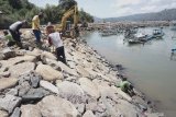 Pekerja dibantu alat berat membangun prasarana tanggul untuk kolam labuh baru di Pelabuhan Pendaratan Ikan (PPI) Popoh, Tulungagung, Jawa Timur, Sabtu (23/11/2019). Revitalisasi PPI Popoh itu bertujuan untuk menambah daya tampung kapal, sehingga kapal bertonase besar dengan daya jangkau tangkapan ikan lebih dari empat (4) mil di perairan lepas pantai bisa masuk dan sandar/lego jangkar di pelabuhan setempat. Antara Jatim/Destyan Sujarwoko/zk.