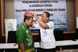 Wakil Pimpinan Permodalan Nasional Madani (PNM) Cabang Surabaya Sugiarto (kanan) memasangkan kopyah bordir kapada Kasi Industri tekstil dan kimia aneka disperindag Pasuruan Misbakhul Munir (kiri) saat pelatihan desain bordir dan teknologi terkini program pengembangan kapasitas usaha Klasterisasi bordir di Bangil, Pasuruan, Jawa Timur, Kamis (28/11/2019). Program yang diadakan oleh PT PNM di daerah tersebut bertujuan untuk meningkatkan daya saing pasar pada usaha bordir melalui pelatihan desain dengan menggunakan teknologi terkini. Antara Jatim/Umarul Faruq/zk