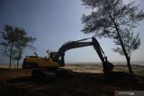 Pekerja menggunakan alat berat untuk pelaksanaan pemulihan (restorasi) garis pantai proyek kilang minyak 