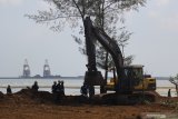 Pekerja menggunakan alat berat untuk pelaksanaan pemulihan (restorasi) garis pantai proyek kilang minyak 