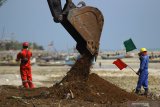 Pekerja menggunakan alat berat untuk pelaksanaan pemulihan (restorasi) garis pantai proyek kilang minyak 