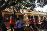 Sejumlah petugas dari kepolisian, koramil, dan warga bergotong-royong menurunkan genteng atap SDN 3 Jamintoro 3, Sumberbaru, Jember, Jawa Timur, Senin (2/12/2019). Gotong royong menurunkan material atap bangunan itu untuk mengantisipasi atap ambruk yang bisa menimbulkan korban, serta untuk mengetahui kondisi kerusakan bangunan. Antara Jatim/Seno/zk.