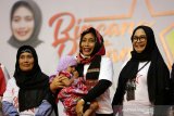 Menteri Pemberdayaan Perempuan dan Perlindungan Anak (PPPA) I Gusti Ayu Bintang Puspayoga (tengah) menggendong anak pelaku usaha rumah tangga saat berdialog tentang program Membina Ekonomi Keluarga Sejahtera (Mekaar) PT Permodalan Nasional Madani (PNM) di Amel Convention Hall, Banda Aceh, Aceh, Kamis (5/12/2019). Pada kunjungan perdana sejak menjabat Menteri PPPA ke provinsi Aceh Bintang Puspayoga mengajak seluruh perempuan untuk mandiri secara ekonomi guna meningkatkan kesejahteraan dan mencegah kekerasan dalam keluarga. Antara Aceh/Irwansyah Putra.