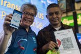 Direktur Utama bank BJB Yuddy Renaldi (kiri) bersama perwakilan pedagang menunjukan bukti transaksi pembayaran digital dengan barcode di Pasar Baru, Bandung, Jawa Barat, Senin (16/12). Bank BJB meluncurkan pembayaran digital dengan menggunakan Quick Response Code Indonesian Standard (QRIS), bjb EDC berbasis Android dan bjb Digi (mobile banking) yang bertujuan untuk mendukung interkoneksi instrumen sistem pembayaran yang lebih luas dan mengakomodasi kebutuhan transaksi keuangan secara nasional. ANTARA JABAR/M Agung Rajasa/agr