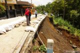 Petugas memeriksa kondisi plengseng jalan yang amblas terseret longsor di jalur menuju lereng Gunung Wilis, Desa Geger, Tulungagung, Jawa Timur, Selasa (17/12/2019). Plengseng jalan di jalur Selingkar Wilis itu amblas terseret longsor akibat hujan deras yang mengguyur wilayah tersebut, sehari sebelumnya. Antara Jatim/Destyan Sujarwoko/zk.