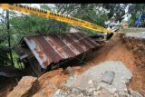 Sebuah rumah amblas terkena bencana tanah bergerak, di tepi jalan Nagari Koto Alam, Kabupaten Limapuluhkota, Sumatera Barat, Sabtu (21/12/2019). Jalan nasional Sumbar - Riau itu diberlakukan buka tutup karena sebagian ruas jalan terimbas bencana tanah bergerak yang juga mengakibatkan empat rumah amblas. ANTARA FOTO/Adi Prima/nym.