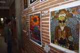 Pengunjung mengamati lukisan saat pameran seni bertema Gliyak Gliyak di Ponorogo, Jawa Timur, Sabtu (21/12/2019). Pameran seni yang sebagian besar memajang karya seni grafis tersebut diikuti puluhan perupa dan berlangsung hingga 24 Desember mendatang. Antara Jatim/Siswowidodo/zk.