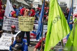 Massa  buruh yang tergabung dari sejumlah serikat pekerja melakukan aksi unjuk rasa di depan Gedung DPRD Jawa Barat, Bandung, Jawa Barat, Senin (23/12/2019).  Aksi tersebut untuk menuntut Gubernur Jawa Barat merevisi SK upah minimum kota/kabupaten tahun 2020 serta menolak revisi UU No 13 tahun 2003 tentang ketenagakerjaan. ANTARA JABAR/Novrian Arbi/agr