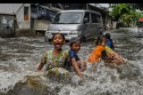 Anak-anak bermain saat banjir melanda kawasan Sunter, Jakarta, Rabu (25/12/2019). Banjir di kawasan tersebut diakibatkan hujan deras dan tersumbatnya saluran air oleh sampah. ANTARA FOTO/Muhammad Adimaja/nym.