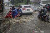 Warga membantu pengendara untuk melintasi derasnya arus air saat hujan deras di kawasan Cikutra, Bandung, Jawa Barat, Jumat (27/12/2019). Genangan air terjadi akibat tingginya intensitas hujan dan buruknya drainase di kawasan tersebut. ANTARA JABAR/Novrian Arbi/agr