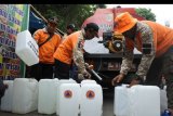 Personel Badan Penanggulangan Bencana Daerah (BPBD) mendistribusikan air bersih di lokasi penyebaran Hepatitis A, Sumbersari, Jember, Jawa Timur, Sabtu (28/12/2019). Dinas Kesehatan Kabupaten Jember dan BPBD setempat melakukan sosialisasi atas penetapan kondisi Kejadian Luar Biasa (KLB) Hepatitis A sekaligus mendistribusikan bantuan air bersih untuk masyarakat menyusul ditemukannya 217 kasus. ANTARA FOTO/Seno/nym