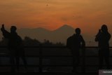 Pengunjung melakukan swafoto saat fajar pertama tahun 2020 di jembatan Kampung Warna-warni Jodipan dengan berlatar belakang gunung Semeru di  Malang, Jawa Timur, Rabu (1/1/2020). Setelah merayakan malam pergantian tahun, sejumlah wisatawan sengaja datang ke kawasan wisata tersebut untuk melihat matahari terbit pertama tahun 2020. Antara Jatim/Ari Bowo Sucipto/zk