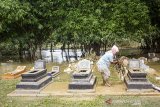 Warga membersihkan makam keluarganya pascabanjir di Desa Karangligar, Karawang, Jawa Barat, Jumat (3/1/2020). Banjir yang melanda permukiman warga di wilayah itu berangsur surut dan menyisakan lumpur serta tumpukan sampah. ANTARA JABAR/M Ibnu Chazar/agr