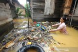 Seorang warga menyingkirkan sampah yang terbawa arus saat banjir di kawasan Cempaka, Banjarbaru, Kalimantan Selatan, Minggu (5/1/2020). Banjir yang disebabkan meluapnya sungai Tiung di kawasan Cempaka tersebut berdasarkan data Badan Penanggulangan Bencana Daerah (BPBD) Kalsel mengakibatkan 70 rumah dan tiga sekolah PAUD terendam. Foto Antaranews Kalsel/Bayu Pratama S.