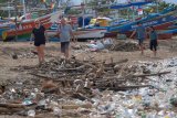 Sejumlah wisatawan melintas di dekat tumpukan sampah yang berserakan di Pantai Kedonganan, Badung, Bali, Selasa (7/1/2020). Pantai bagian selatan Bali tersebut mulai dicemari sampah kayu, rumput laut dan plastik yaitu limbah dari daerah lain yang terbawa gelombang laut disertai angin kencang. ANTARA FOTO/Nyoman Hendra Wibowo/nym.