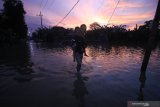 Warga menggendong anaknya saat berjalan di tengah banjir di Desa Guranganyar, Kecamatan Cerme, Gresik, Jawa Timur, Rabu (8/1/2020). Delapan desa di kecamatan tersebut terendam banjir akibat luapan air Kali Lamong. Antara Jatim/Moch Asim/zk.