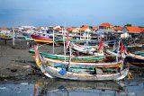 Warga melintas didekat perahu yang ditambatkan di Pelabuhan Branta Pesisir, Pamekasan, Jawa Timur, Jumat (10/1/2020). Dalam beberapa hari terakhir sejumlah nelayan di daerah itu, tidak melaut karena cuaca ekstrim. Antara Jatim/Saiful Bahri/zk