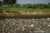 Warga melintas di samping sampah plastik yang menutupi permukaan Sungai Cikeruh yang bermuara ke Sungai Citarum di Sukarame, Cileunyi, Kabupaten Bandung, Jawa Barat, Selasa (21/1/2020). Warga menyatakan, sampah rumah tangga yang terbawa luapan air akibat hujan deras pada Senin (20/1) sore tersebut dapat dibersihkan oleh pihak terkait karena menimbulkan bau yang tidak sedap dan dapat menimbulkan berbagai penyakit. ANTARA JABAR/Raisan Al Farisi/agr