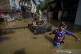 Seorang anak menarik perahu karet yang membawa ibunya saat banjir yang melanda Kampung Bojongasih, Dayeuhkolot, Kabupaten Bandung, Jawa Barat, Jumat (24/1/2020). Banjir luapan Sungai Citarum dengan ketinggian maksimal 1,5 meter tersebut diakibatkan oleh hujan deras pada Kamis (23/1) sore hingga malam hari di beberapa wilayah Bandung Raya dan menyebabkan ratusan warga mengungsi. ANTARA JABAR/Raisan Al Farisi/agr